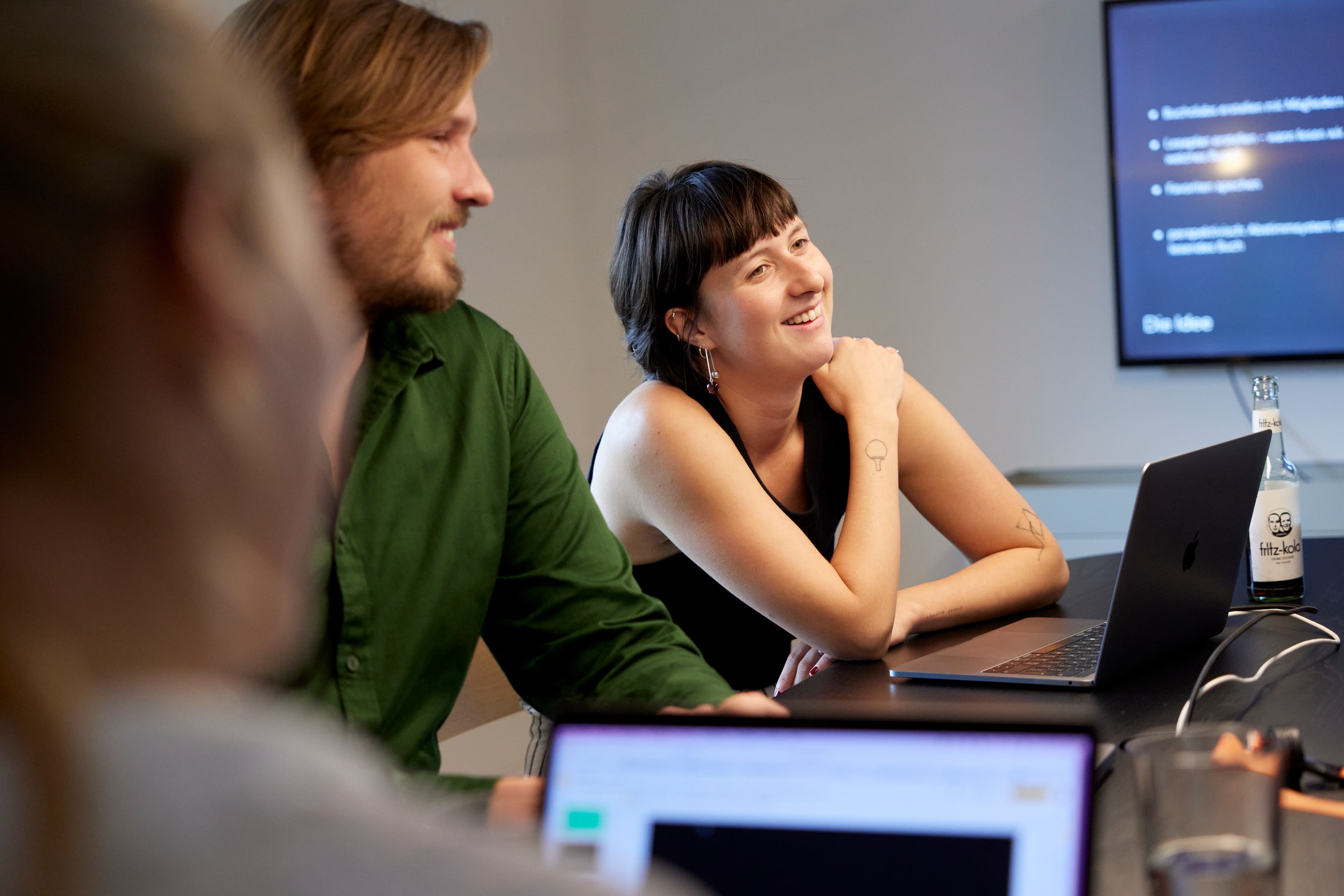 Drei Personen am Tisch im Besprechungsraum mit Fokus auf einer der Personen
